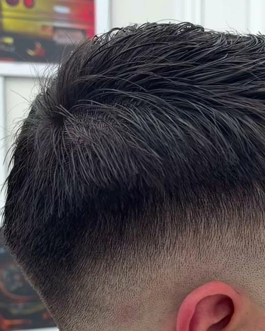 Side view of a mid drop fade around the ear, textured on top